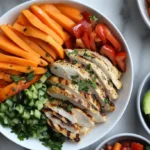 An assortment of vibrant low-histamine dishes arranged on a rustic table, including a quinoa salad with fresh cucumbers and blueberries, baked sweet potato wedges, grilled chicken breast, and a refreshing herbal tea, emphasizing wholesome, anti-inflammatory ingredients.