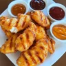 Grilled Chick-fil-A style nuggets on a plate with dipping sauces.