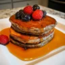3-ingredient eggless pancakes topped with fresh berries and maple syrup.