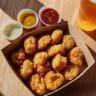 Taco Bell Crispy Chicken Nuggets with dipping sauces on a wooden table.
