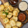 Golden, crispy canned chicken nuggets served with sauces on a rustic wooden board.