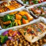 Colorful assortment of healthy sheet pan dinners featuring roasted vegetables, salmon, chicken, and meatballs on parchment-lined baking trays in a cozy kitchen setting.