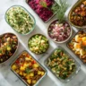 Overhead view of assorted Passover side dishes on a marble countertop with fresh herbs and lemon garnishes.