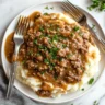 Top-down view of ground beef and gravy over mashed potatoes.