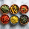 Overhead shot of six Mexican vegetable side dishes on marble countertop