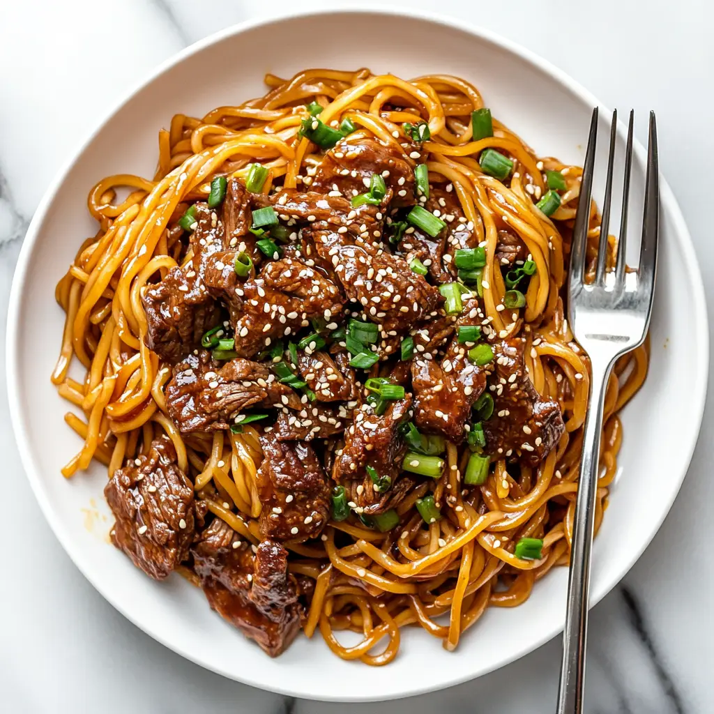 A luscious skillet of Mongolian beef noodles with tender beef, bright broccoli, and sesame seeds.