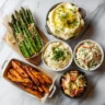 spread of lemon-garlic asparagus, mashed potatoes, coleslaw, and sweet potato fries
