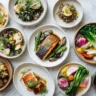 Ten beautifully plated low histamine dinner dishes arranged on a marble surface under natural lighting