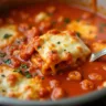 Instant Pot lasagna soup served in a white bowl, topped with melted cheese and fresh basil, with a spoon resting on the side and the Instant Pot in the background.
