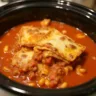 Crock pot filled with hearty lasagna soup, featuring rich tomato broth, ground meat, pasta, and melted cheese, garnished with fresh basil and ready to serve.